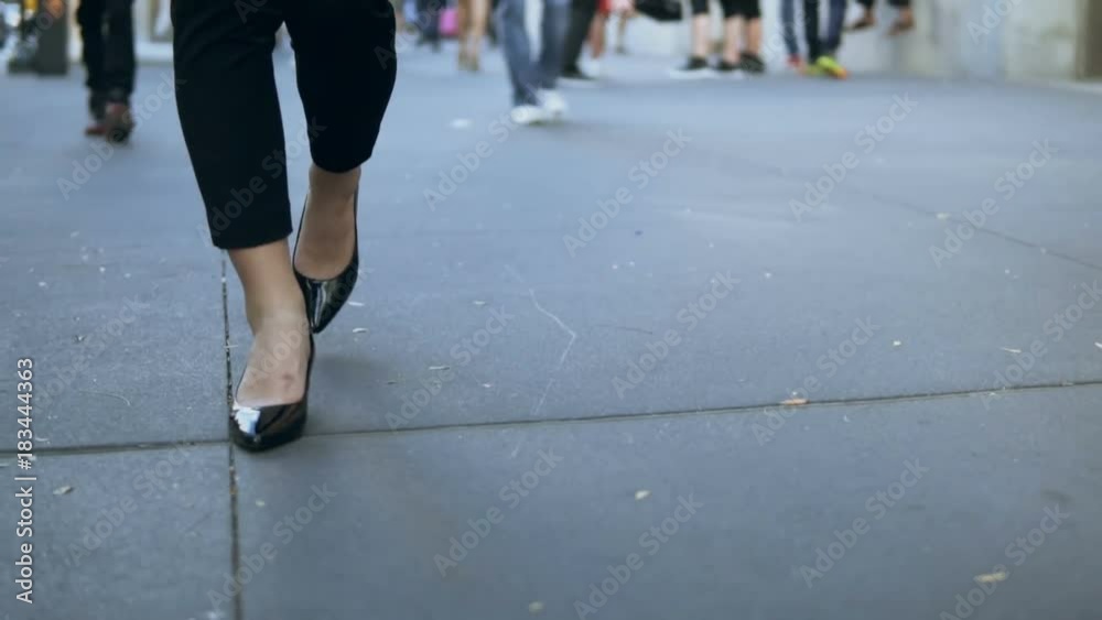 Close-up view of young female walking through the downtown. Businesswoman wearing black shoes with heels. Slow motion. Close-up view of young female walking through the downtown. Businesswoman wearing black shoes with heels. Slow motion.