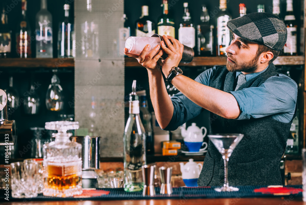Portrait of barman preparing cocktails, using shaker and pouring beverages