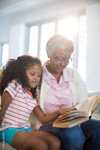 Grandmother and daughter reading book in living room