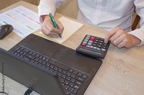 Close up of male hands on her calculator s keyboard. The second hand in on the touchpad. Concept of accountant s work