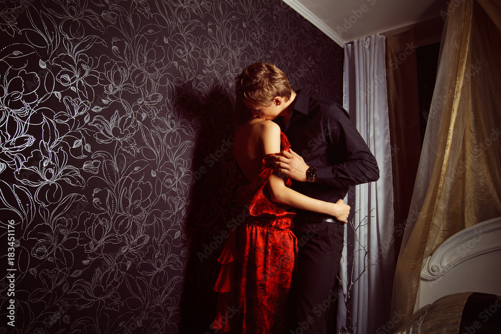 Beautiful young couple is embracing and kissing at bedroom wall background. Beautiful young couple is embracing and kissing at bedroom wall background.