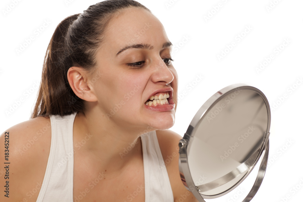 young woman checking her teeth in the mirror young woman checking her teeth in the mirror