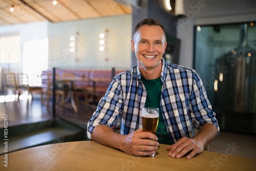 Portrait of smiling man having glass of beer at counter