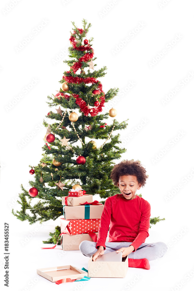 Portrait of cute mixed race little boy unpacking gifts near Christmas tree and taking digital tablet out of box Portrait of cute mixed race little boy unpacking gifts near Christmas tree and taking digital tablet out of box