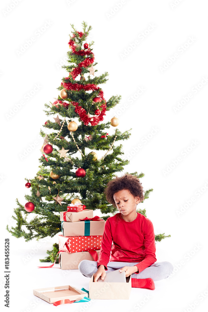 Portrait of cute mixed race little boy unpacking gifts near Christmas tree and taking digital tablet out of box Portrait of cute mixed race little boy unpacking gifts near Christmas tree and taking digital tablet out of box
