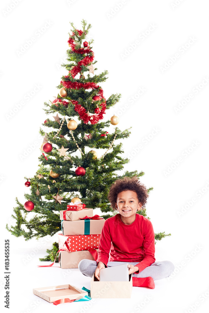 Portrait of cute mixed race little boy unpacking gifts near Christmas tree and taking digital tablet out of box Portrait of cute mixed race little boy unpacking gifts near Christmas tree and taking digital tablet out of box