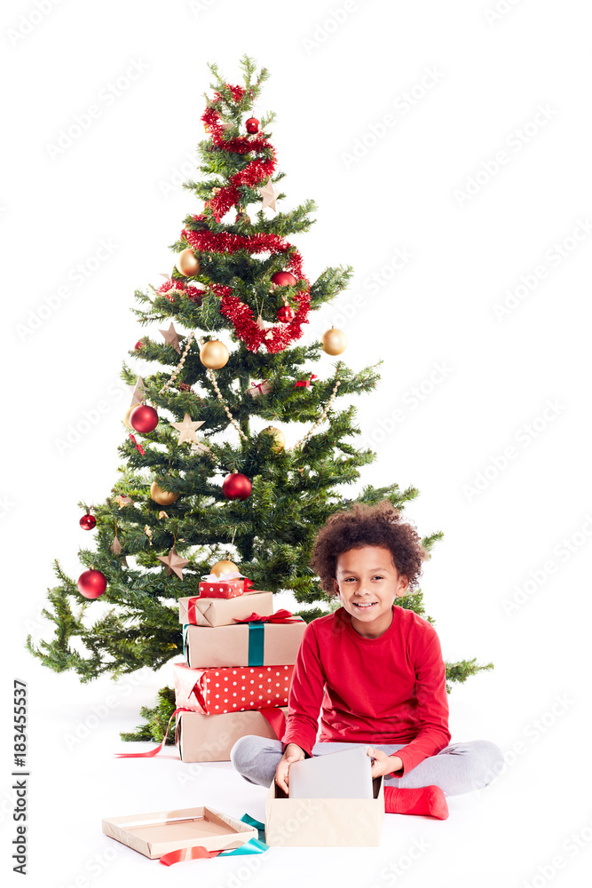 Portrait of cute mixed race little boy unpacking gifts near Christmas tree and taking digital tablet out of box Portrait of cute mixed race little boy unpacking gifts near Christmas tree and taking digital tablet out of box