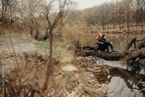 Sweet couple sitting on a hill and looking at the autumn landscape