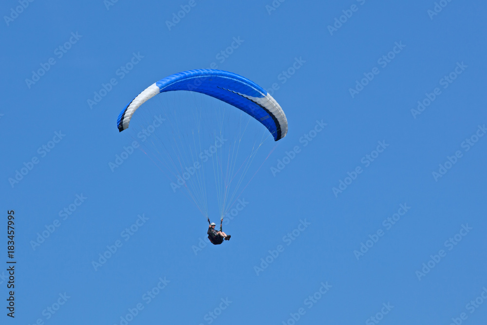 Vol en parapente avec aile bleue et blanche sur fond de ciel bleu d'été dans les Alpes. Vol en parapente avec aile bleue et blanche sur fond de ciel bleu d'été dans les Alpes.