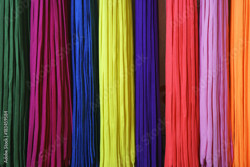 colorful shoe laces. rainbow colored shoe laces hanging next to each other. green  pink  blue  yellow  orange shoe laces.