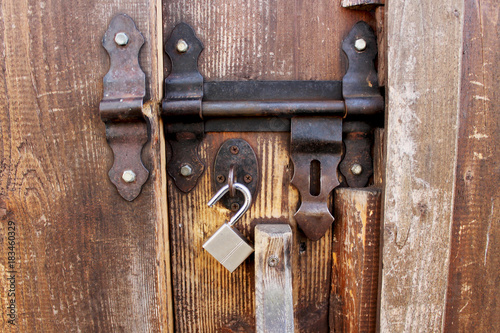 Locked padlock with chain at wooden door background, vintage, Closeup