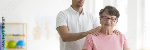 Professional physiotherapist massaging senior woman