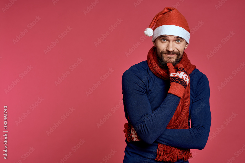 man with a beard in a New Year's cap and gloves, emotions, new year, holiday, christmas, red background, free space for copying man with a beard in a New Year's cap and gloves, emotions, new year, holiday, christmas, red background, free space for copying