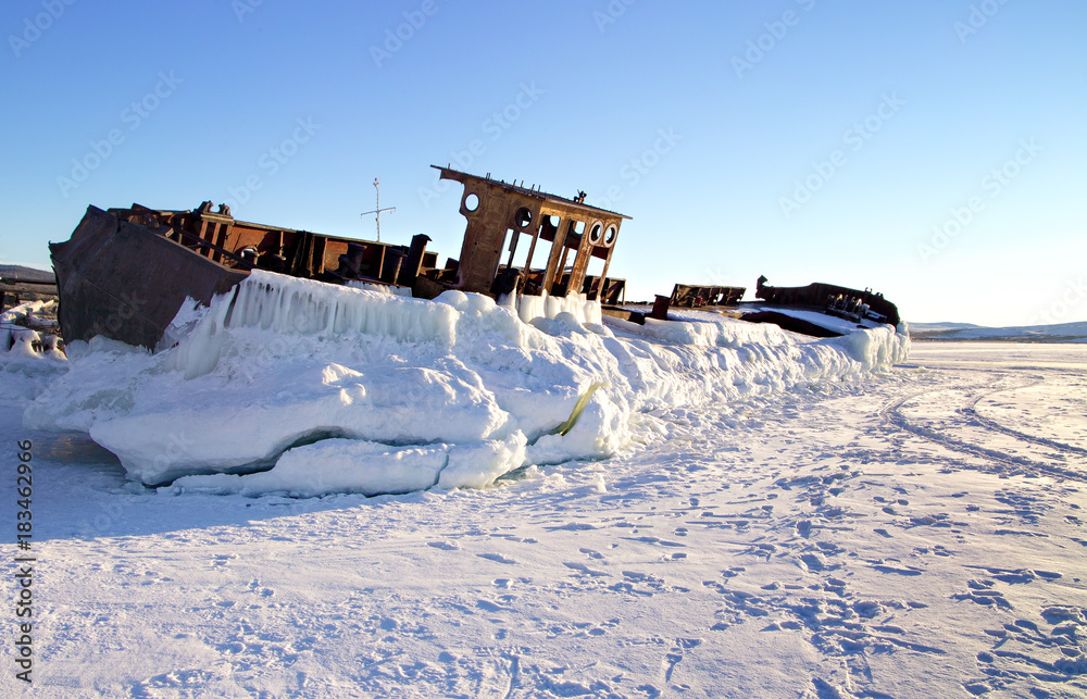 The abandoned old rusty ship placing on the coast of frozen lake. Baikal, Russia The abandoned old rusty ship placing on the coast of frozen lake. Baikal, Russia