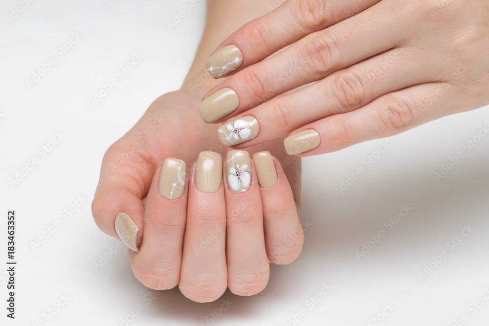 cream, beige manicure on square short nails with painted white orchids on a white background cream, beige manicure on square short nails with painted white orchids on a white background