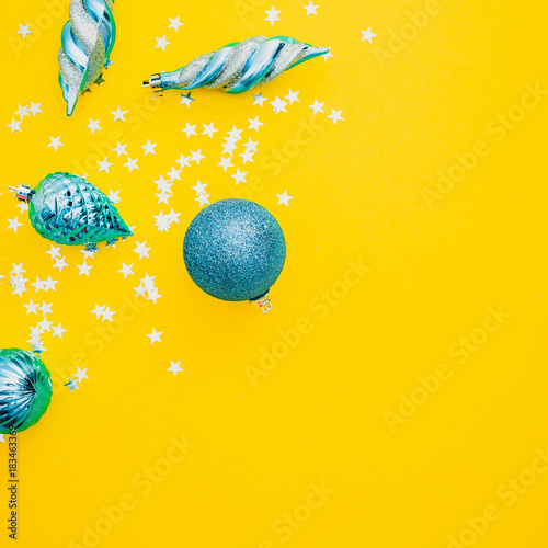 Christmas or New Year composition. Christmas blue balls and silver confetti on yellow background. Flat lay  top view