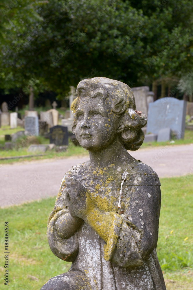 Praying child statue on grave in cemetery