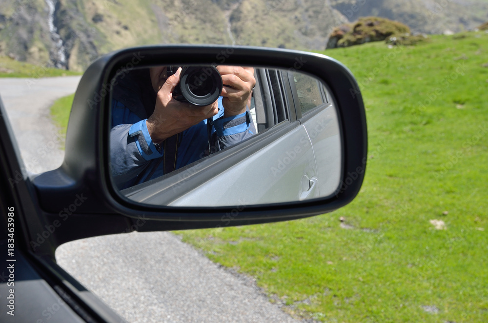 Wing mirror showing a camera in human hands