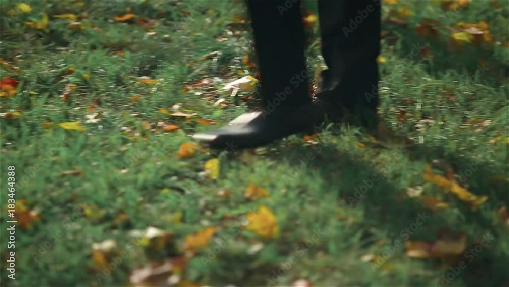 Camera follows man's legs which are walking along green grass lawn. Real time vide Camera follows man's legs which are walking along green grass lawn. Real time vide