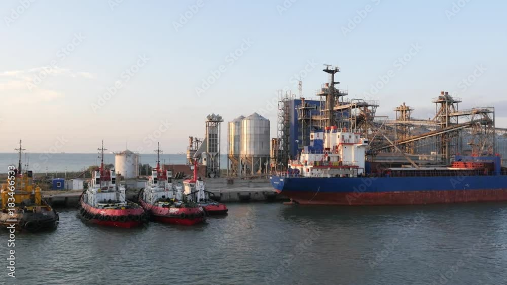 seaport at sunset, moored ships and Tow boat and water tank in the background, Port Kavkaz, Russia. seaport at sunset, moored ships and Tow boat and water tank in the background, Port Kavkaz, Russia.