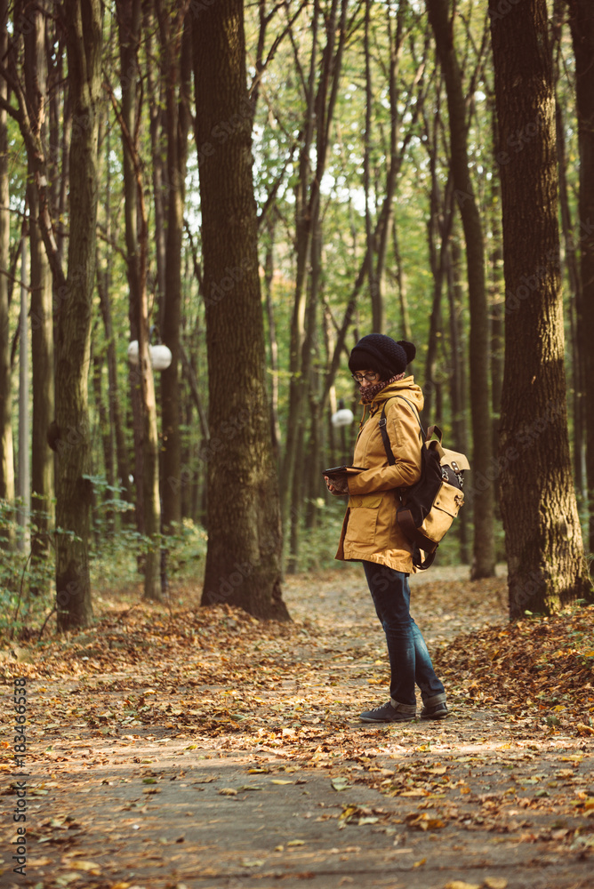 Young stylish hipster girl standing in the autumn park and reading, retro vintage image