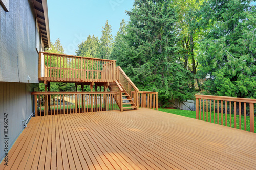 Backyard view of grey rambler house with upper and lower decks photo