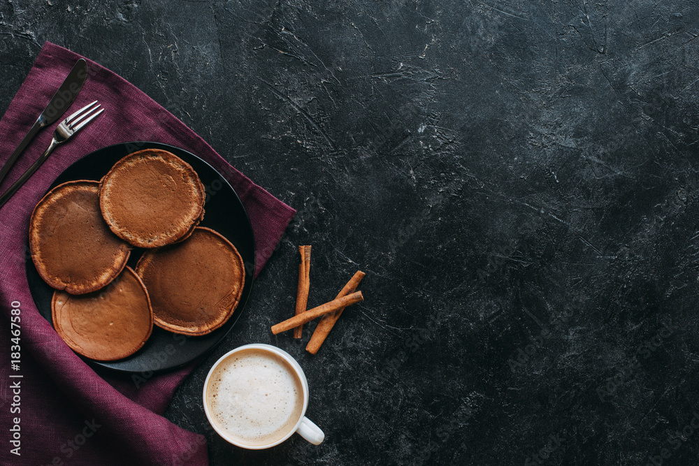 top view of chocolate pancakes and cup of coffee on black concrete table