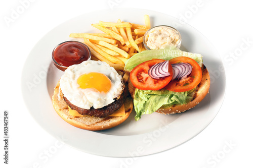 Opened cheese burger with grilled cutlet, cheese, scrambled egg with yolk, tomato, onion, two kind of sauces and salad, as well as roasted potatoes On a round plate. Isolated on white