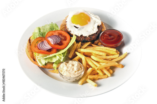 Fast food. Cheeseburger with grilled beef cutlet, cheese, scrambled eggs with yolk, tomato, onion, two kind of sauces and salad. Roasted potato. On a round plate. Isolated on white