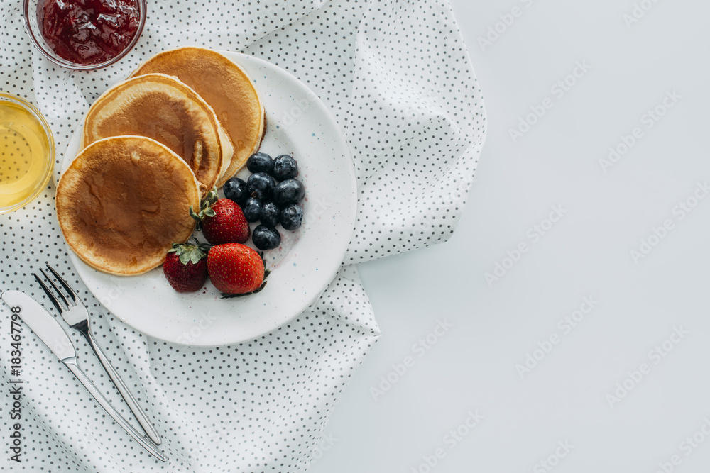 top view of plate of delicious pancakes with berries on white table