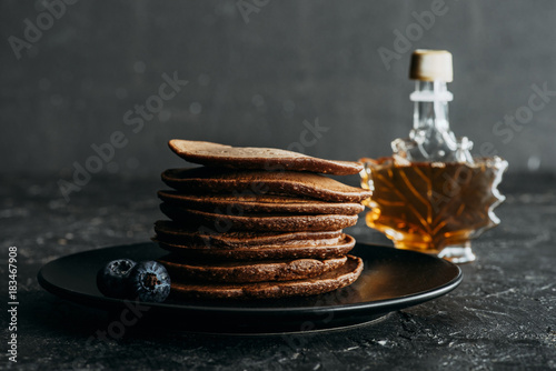 stacked chocolate pancakes with bottle of maple syrup photo