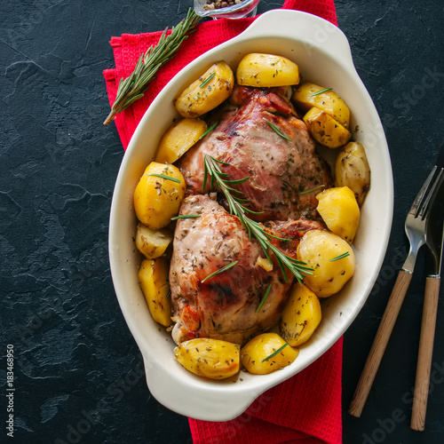 Roasted turkey with rozemary and potatoes in a dish on a black stone background. Festive dinner. Square image. photo