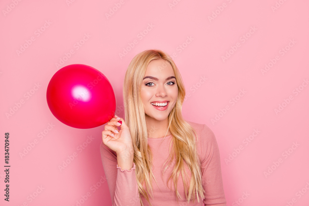 Close up portrait of happy woman raised up hand with balloon, posing for photo, standing over pink background Close up portrait of happy woman raised up hand with balloon, posing for photo, standing over pink background