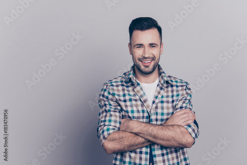 Portrait with copy space of young attractive, stunning, smiling man having his hands crossed, looking at camera, standing over grey background photo