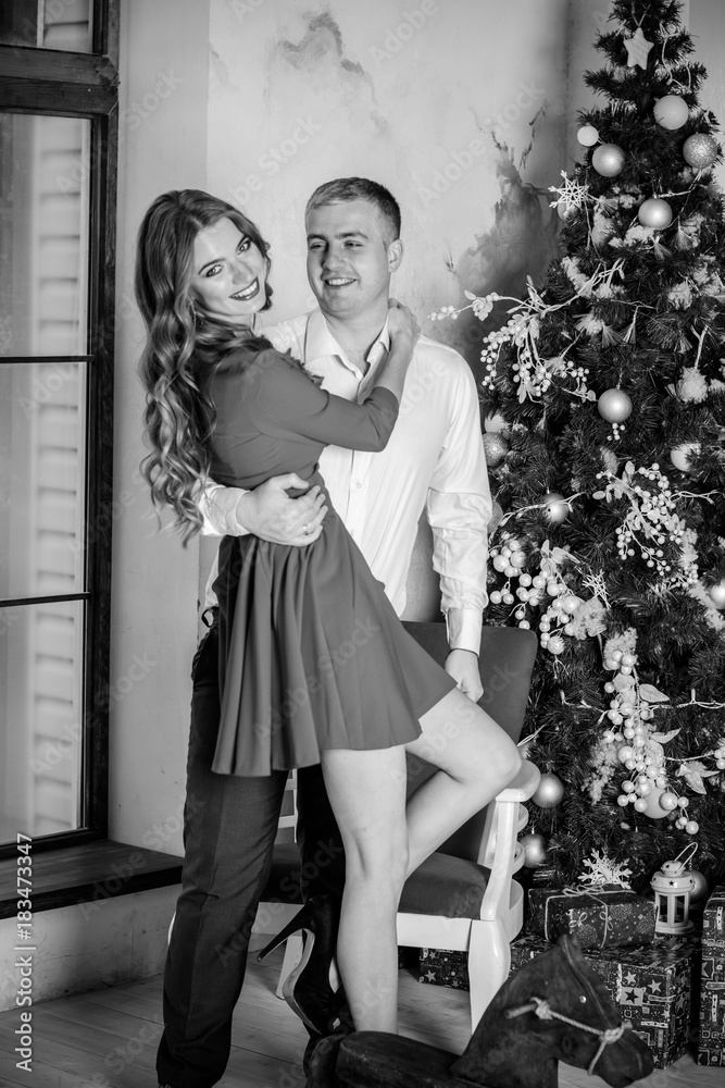 Happy elegant young man holding his girlfriend in his arms at christmas time and make a wish. Inspire new Year for couple, romantic time