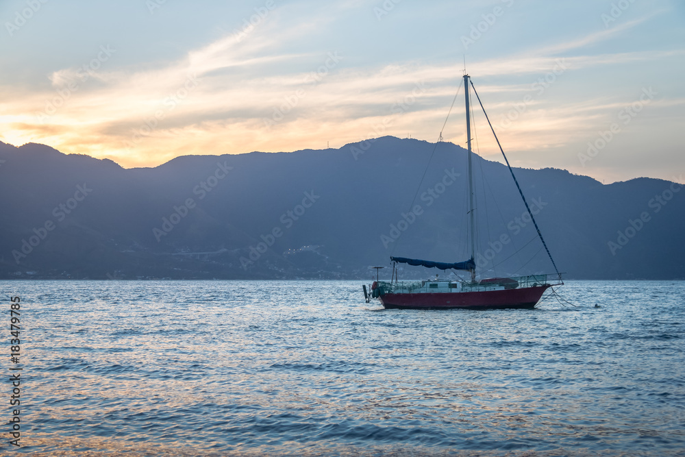 Sailboat at sunset with Sao Sebastiao on background - Ilhabela, Sao Paulo, Brazil