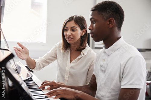 Fototapeta Male Pupil With Teacher Playing Piano In Music Lesson