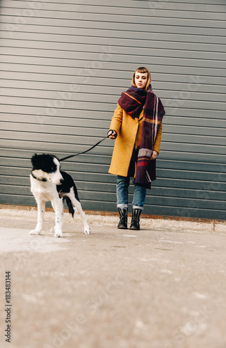 selective focus of young woman with puppy on dog lead standing on street