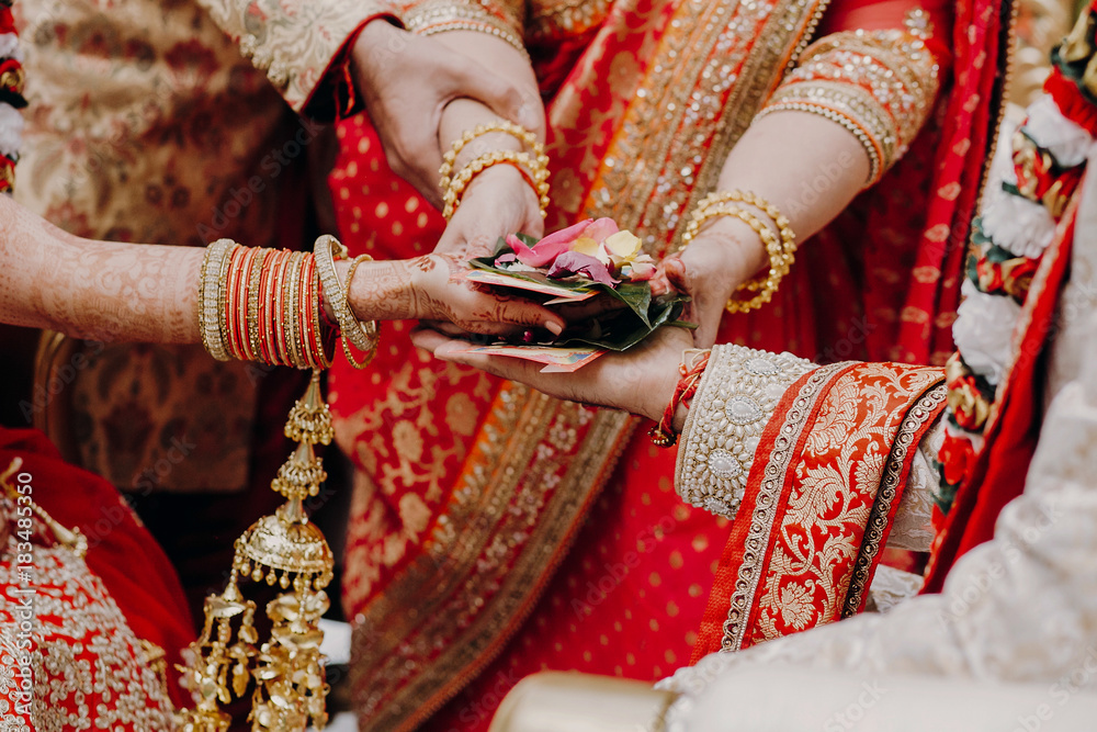 Tender hands of an Indian bride covered with henna tattoo hold groom's hands during the Septapadi ceremony