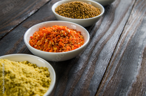 different spices in wooden spoons on a black wooden background