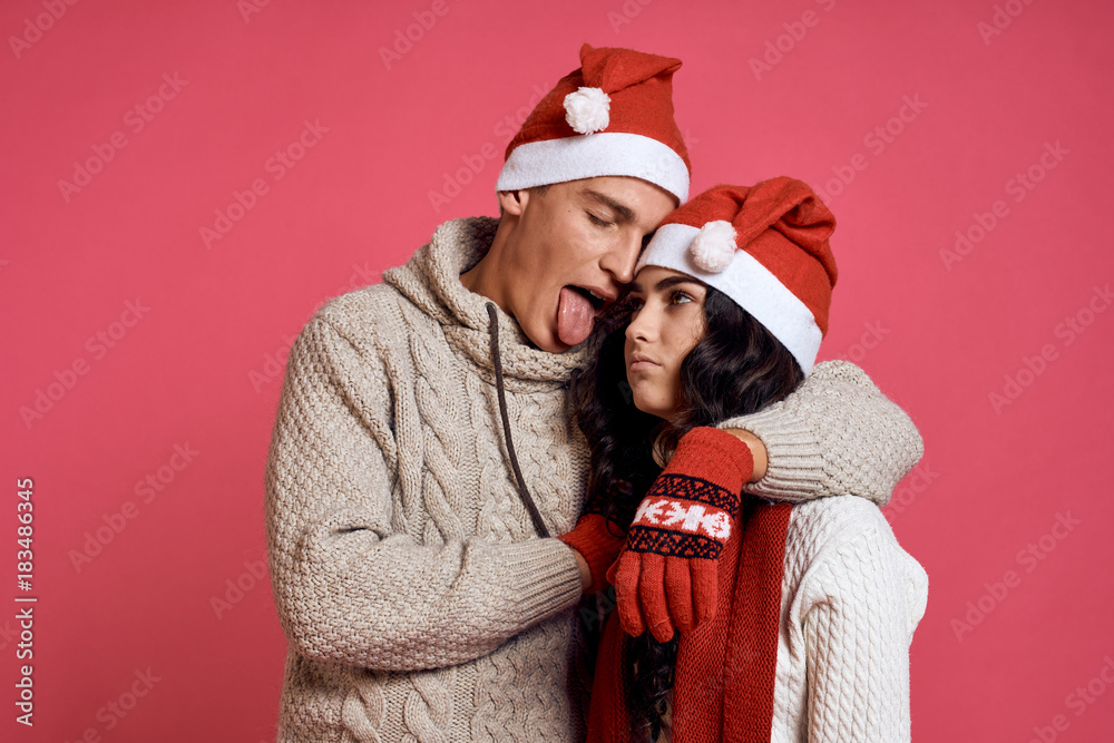 2084066 man sticks out his tongue and hugs a woman, couple, holiday, christmas, new year, winter, red background 2084066 man sticks out his tongue and hugs a woman, couple, holiday, christmas, new year, winter, red background