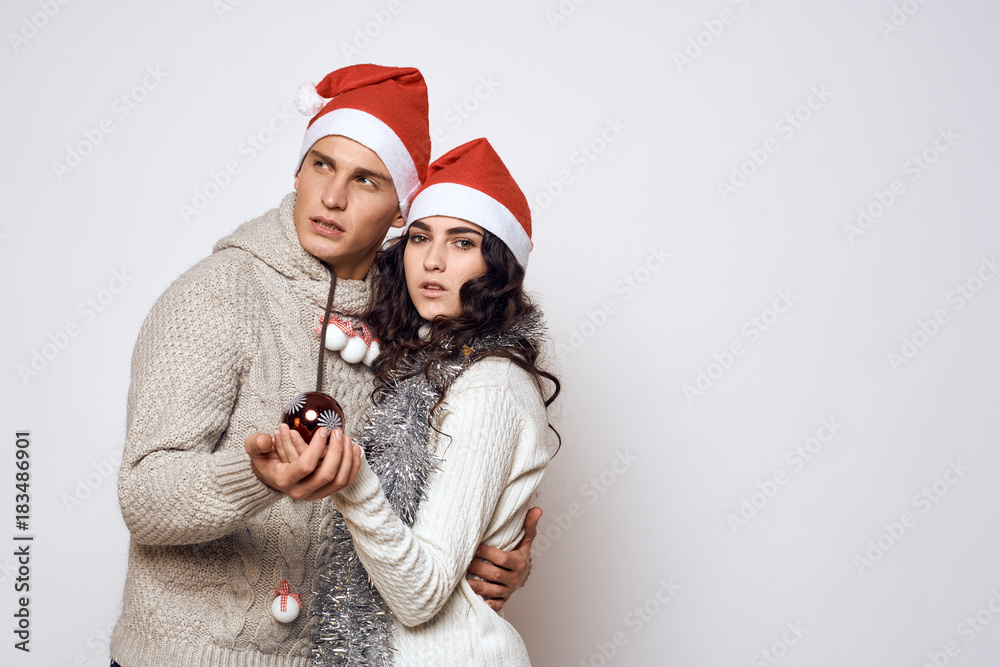Fototapeta premium man and woman are hugging, holding a Christmas tree decoration in the hand christmas, new year, holiday, couple, light background, free space for copy