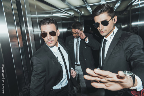 Bodyguard stopping paparazzi when celebrity standing in elevator photo