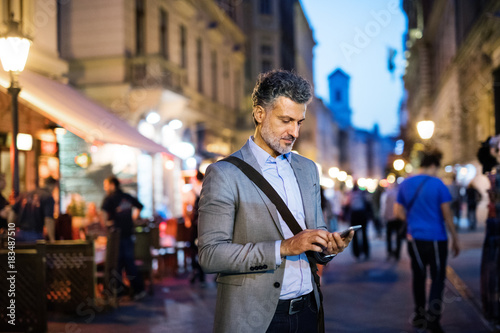 Photography Mature businessman with a smartphone in a city.