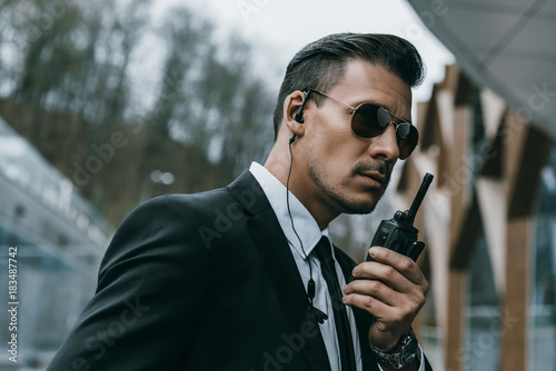 Tableau sur toile serious handsome security guard talking by portable radio