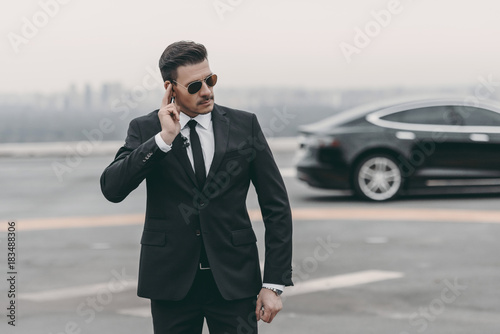 serious bodyguard listening message with security earpiece on helipad