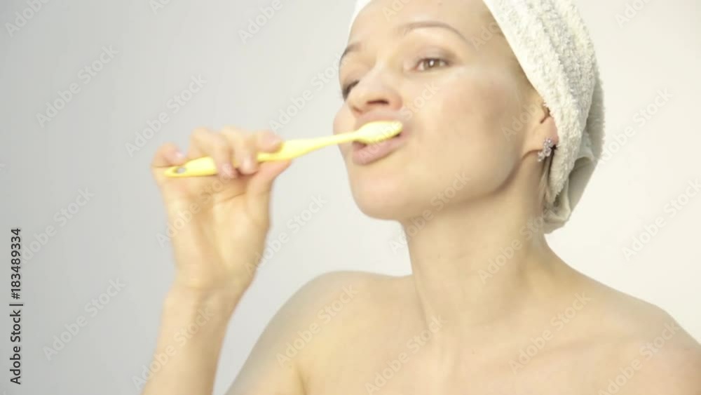 Young beautiful woman with towel on a head brushing her teeth and dancing Young beautiful woman with towel on a head brushing her teeth and dancing