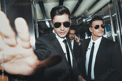 bodyguards stopping paparazzi when celebrity talking by smartphone photo