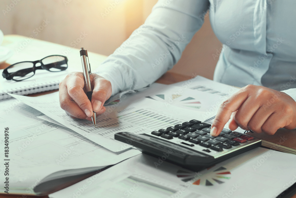 Fototapeta premium businesswoman working in office on desk using calculator and pen