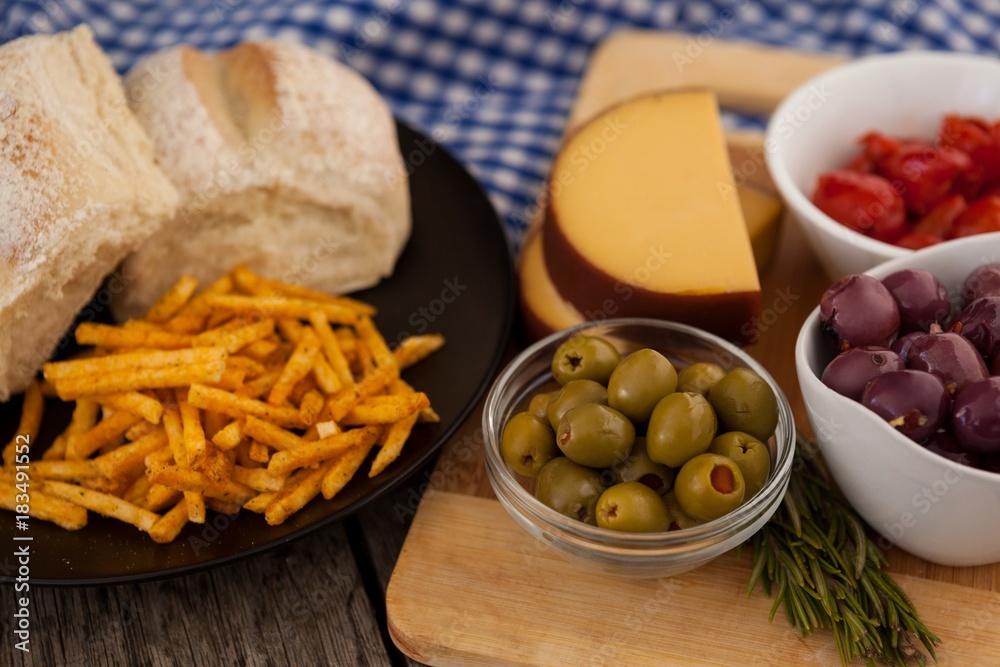 French fries with bread by olives and vegetables on cutting